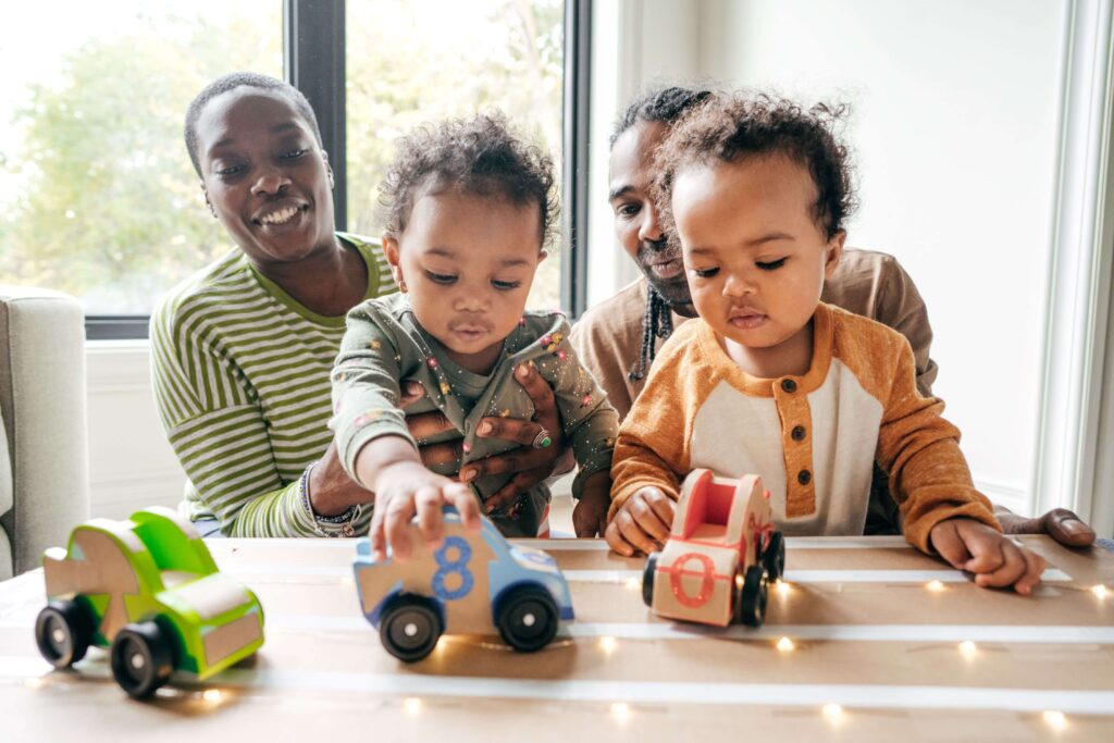 A mom and dad supervise as their kids learn to drive "pretend" cars.