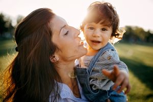 Here, a mom hugs her little boy on a sunny day.